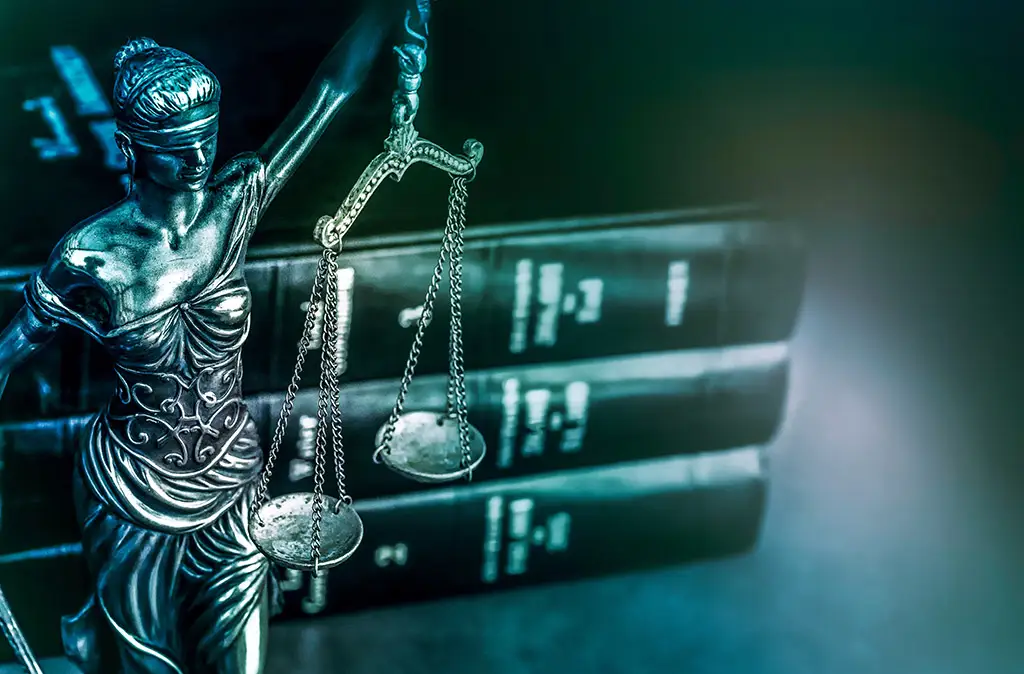 Justitia-Statue vor Gesetzbüchern